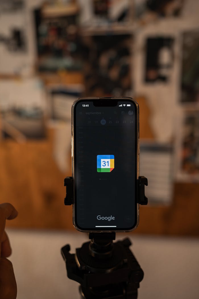 Close-up of a smartphone on a tripod featuring a calendar app with blurred background.